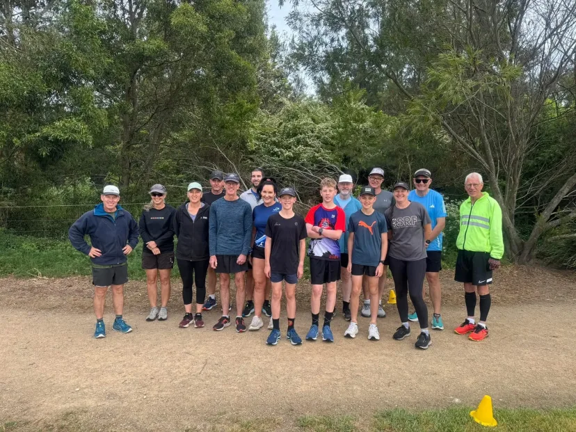 Club members lined up across a dirt trail before a run