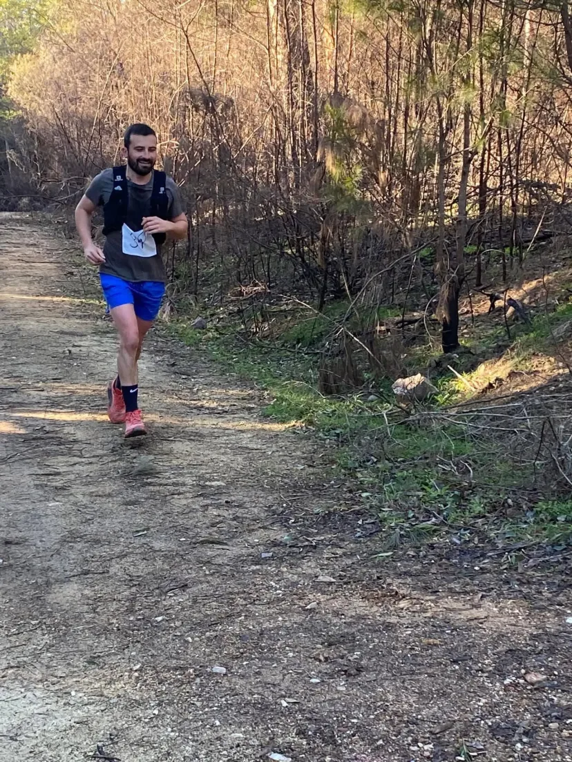 Runner on a wide dirt fire trail through regrowth bush