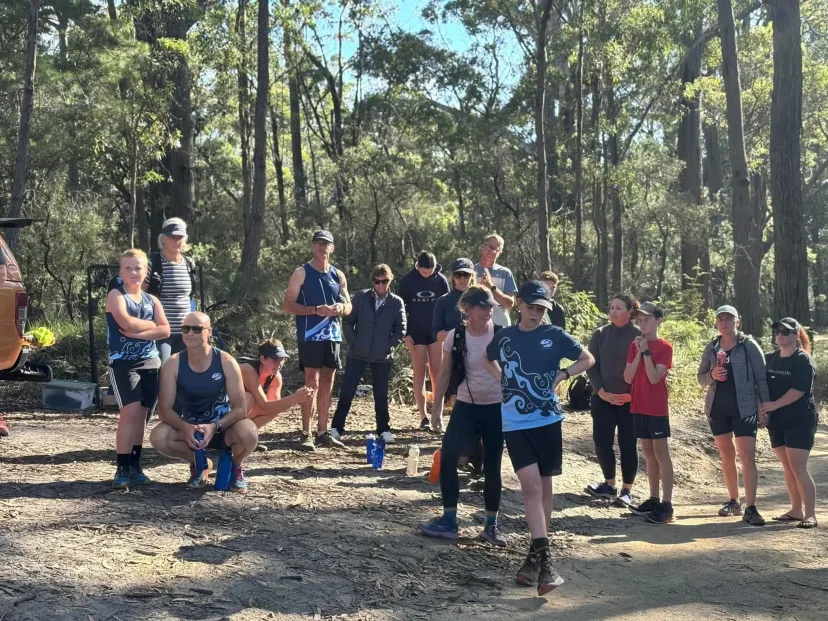 Club members gathered on a trail among tall eucalypts