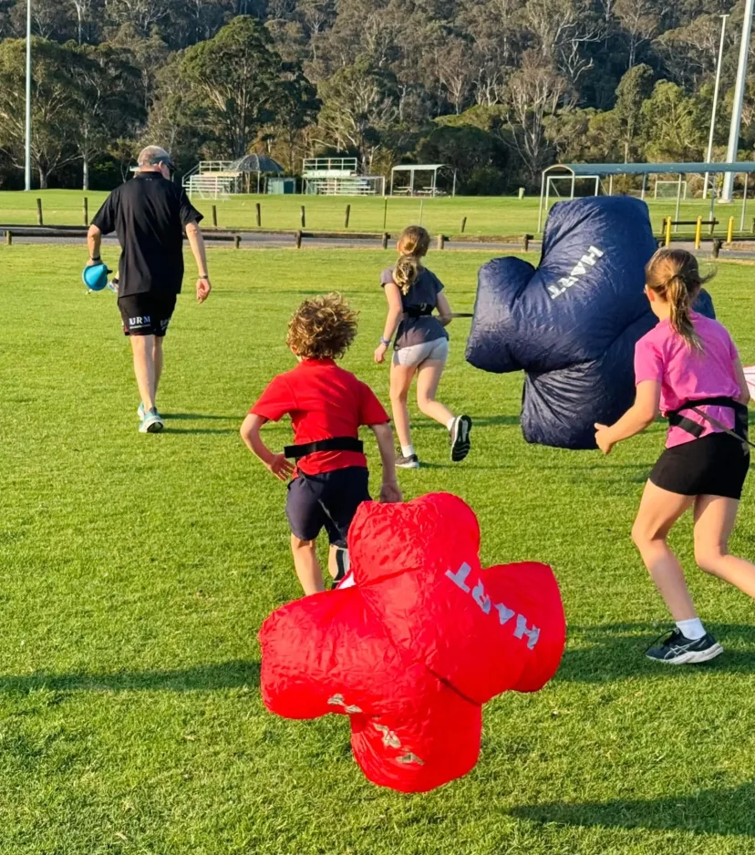 Junior runners playing a game with soft obstacles on the oval