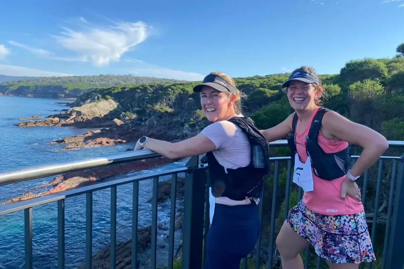 Two runners at a headland lookout above the ocean