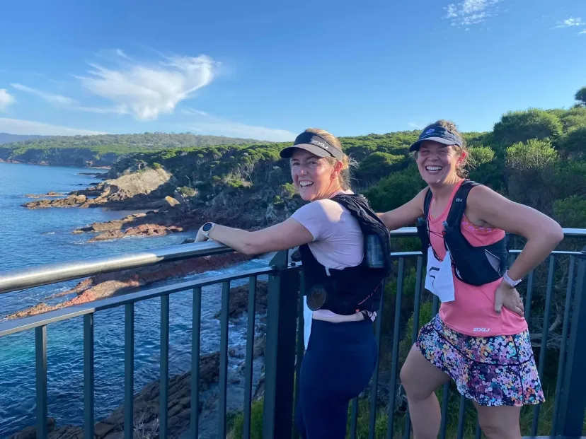 Two runners at a headland lookout above the ocean