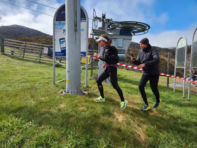 Two runners passing the chairlift on a grassy slope