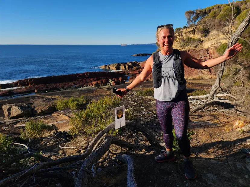 Runner with arms outstretched on a rocky stretch of coast