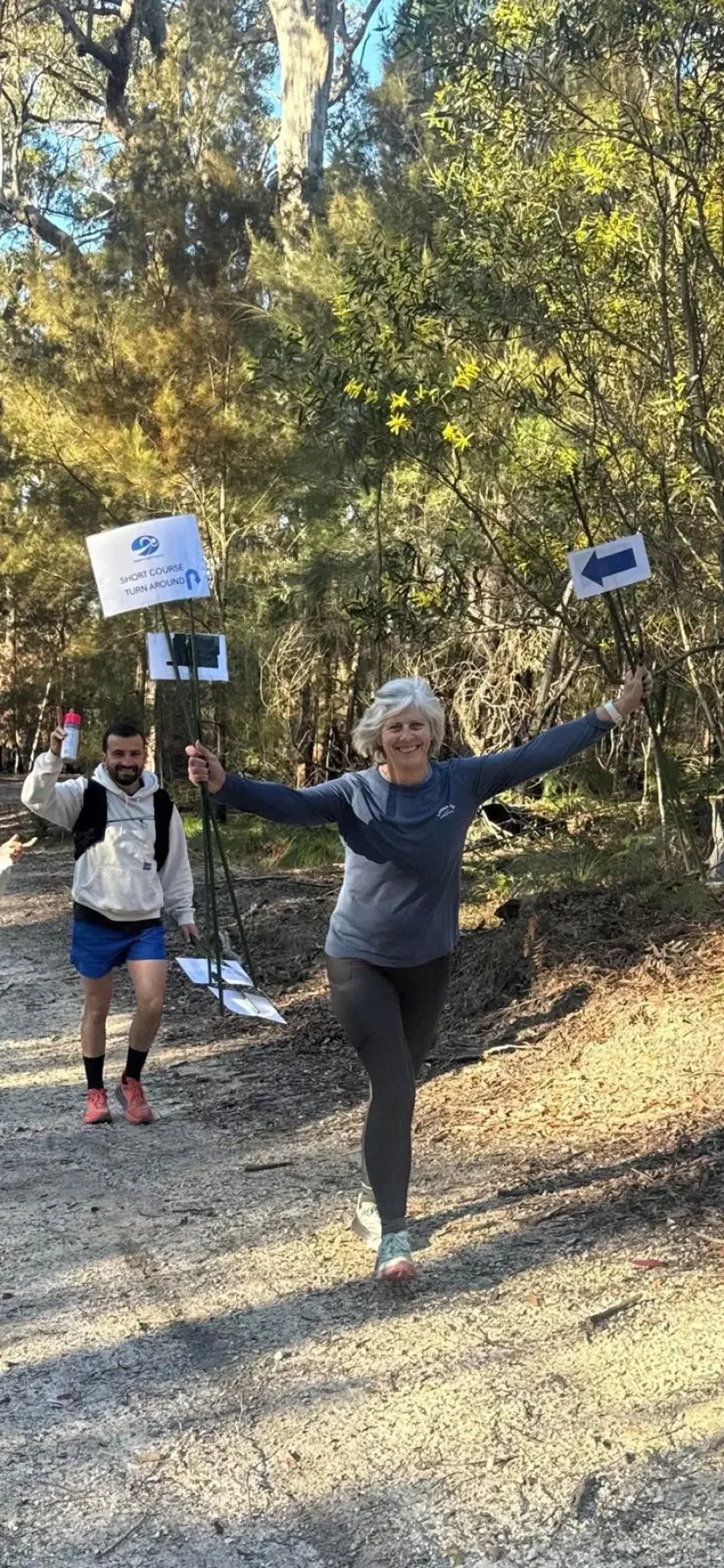 Runner celebrating with arms raised on the trail