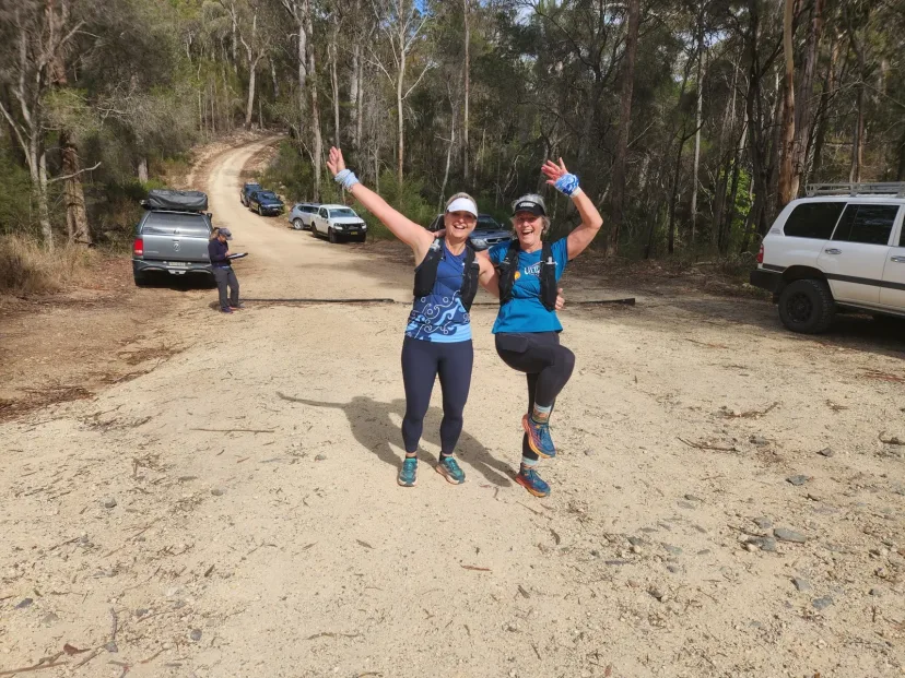 Runner celebrating with arms raised on the trail