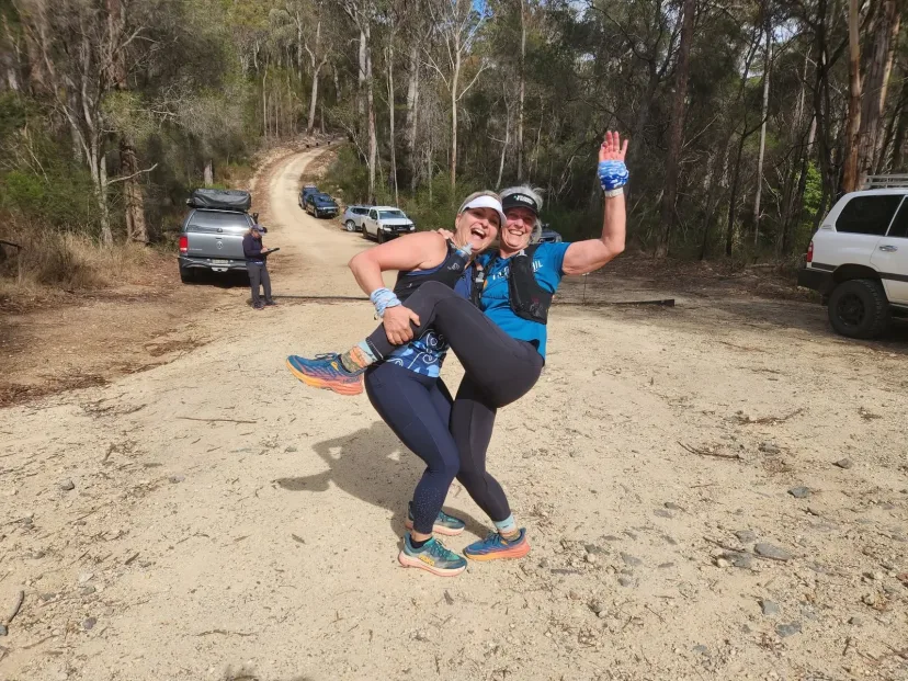 Runner celebrating with arms raised on the trail